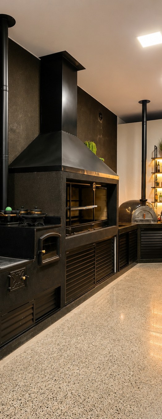 Espaço gourmet com churrasqueira preta, coifa e forno de pizza
